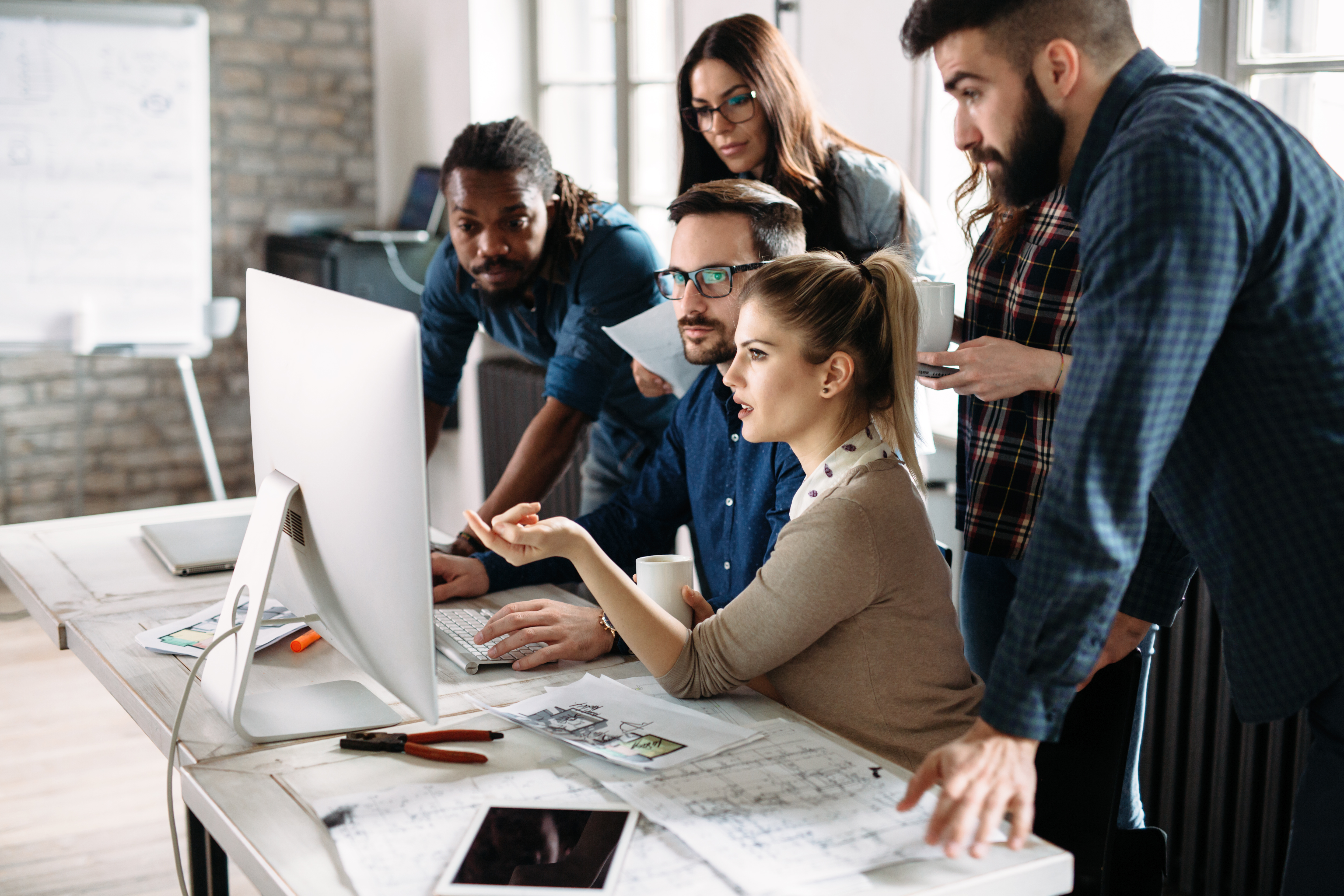 Featured image: Team discussing ideas in from of a computer - Read full post: Career Development: How to Recognise Growth at Work
